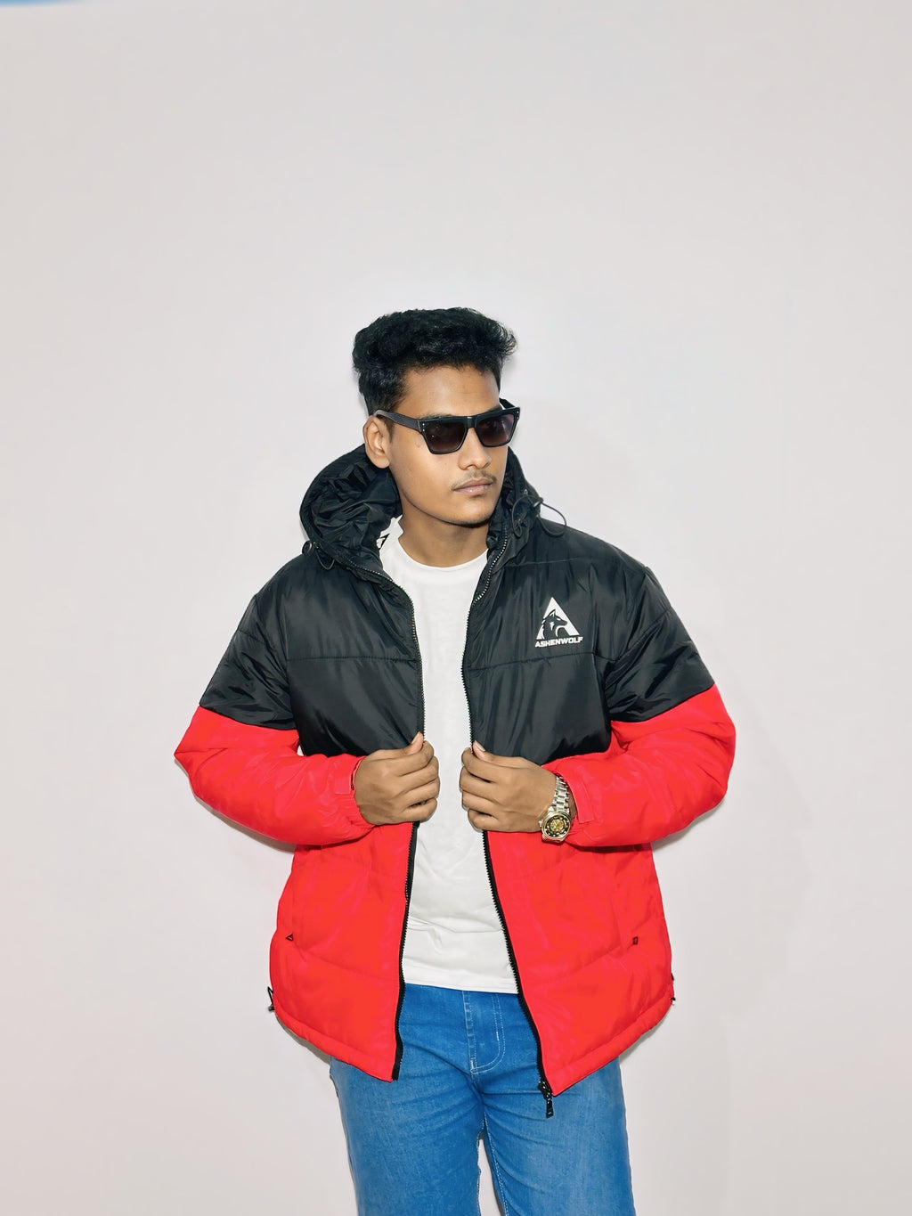 Model wearing sunglasses and a red and black Ashenwolf puffer jacket, front view with jacket partially unzipped.